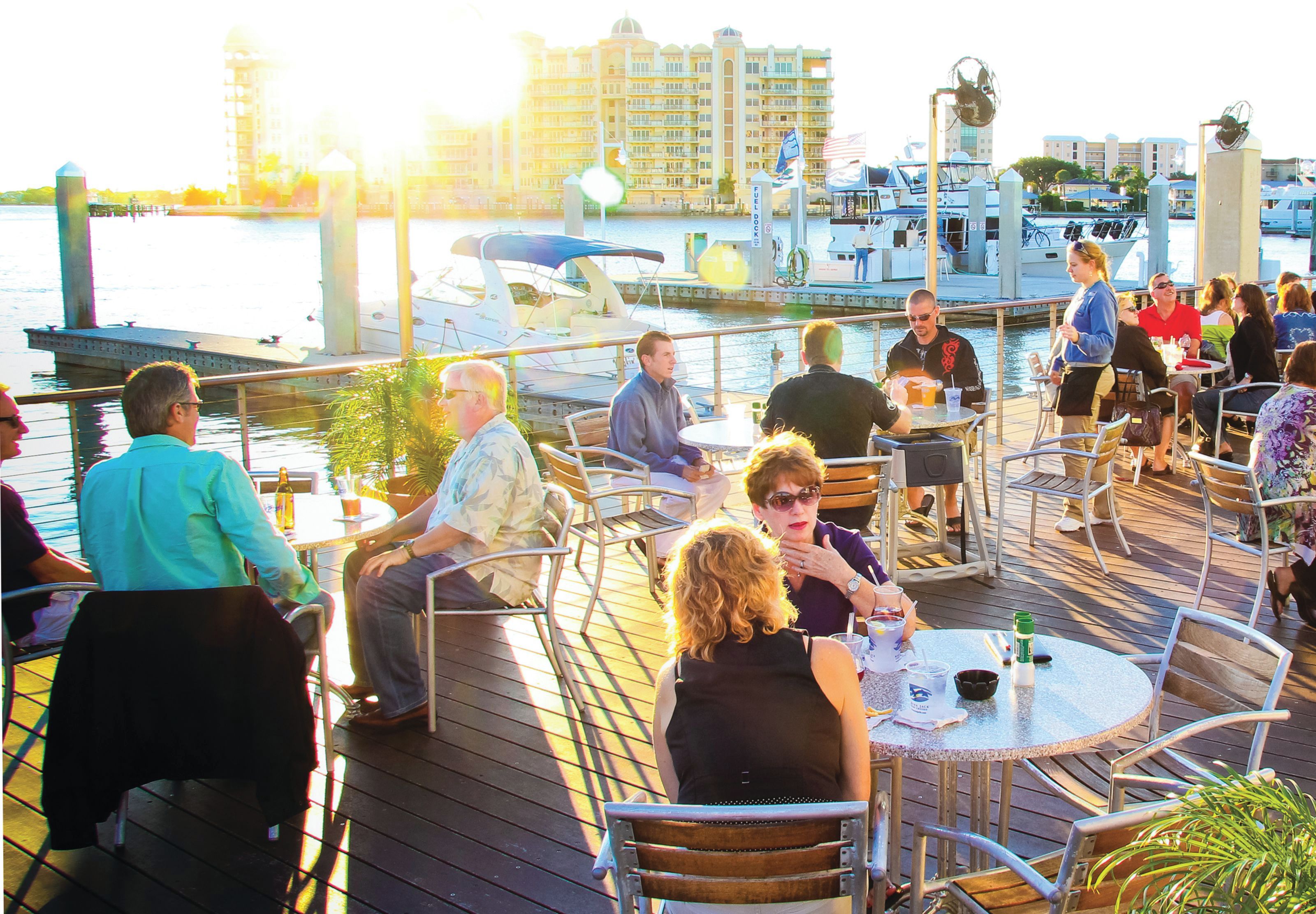 Terraza con asientos al aire libre que da a un puerto deportivo, con barcos y vistas al frente marítimo.