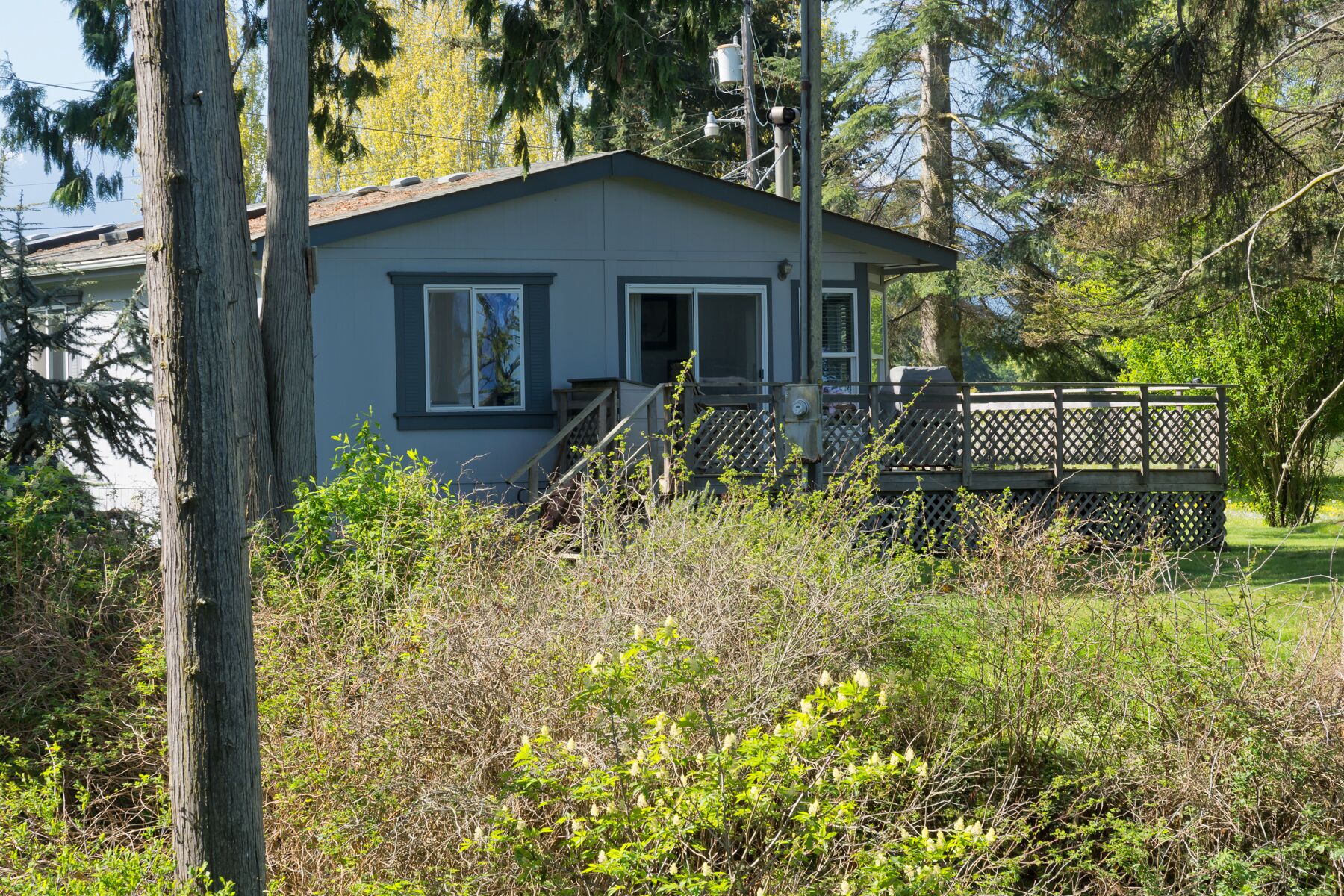 A small, single-story house with a front porch and a wooden deck.