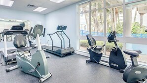 Une salle de sport équipée de tapis de course, de vélos d’appartement et d’autres appareils d’exercice.