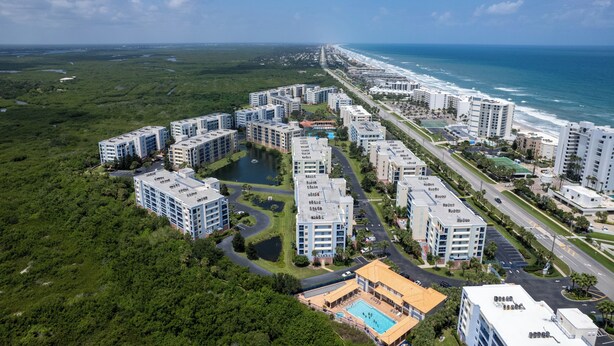 Un quartier résidentiel situé sur la côte, avec de grands immeubles, une plage et une piscine.