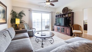 Un salon avec un canapé, une table basse, un téléviseur et une bibliothèque.