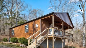 A wooden cabin with a porch, a staircase, and a deck.