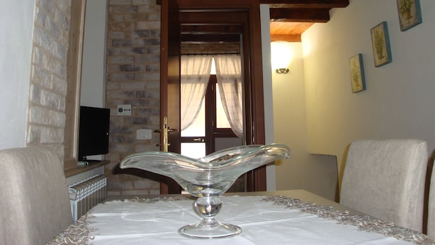 Una habitación con una mesa dispuesta para comer, un televisor sobre un mueble y una pared de ladrillo.