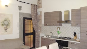 Una cocina compacta con zona de comedor, un sofá y un jarrón decorativo.
