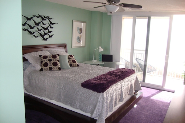 queen primary bedroom with ocean front balcony, modern desk and chair