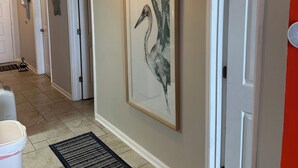 Ein Flur mit einem gerahmten Kunstwerk mit Vogelmotiv, einer weißen Tür und einer roten Wand.