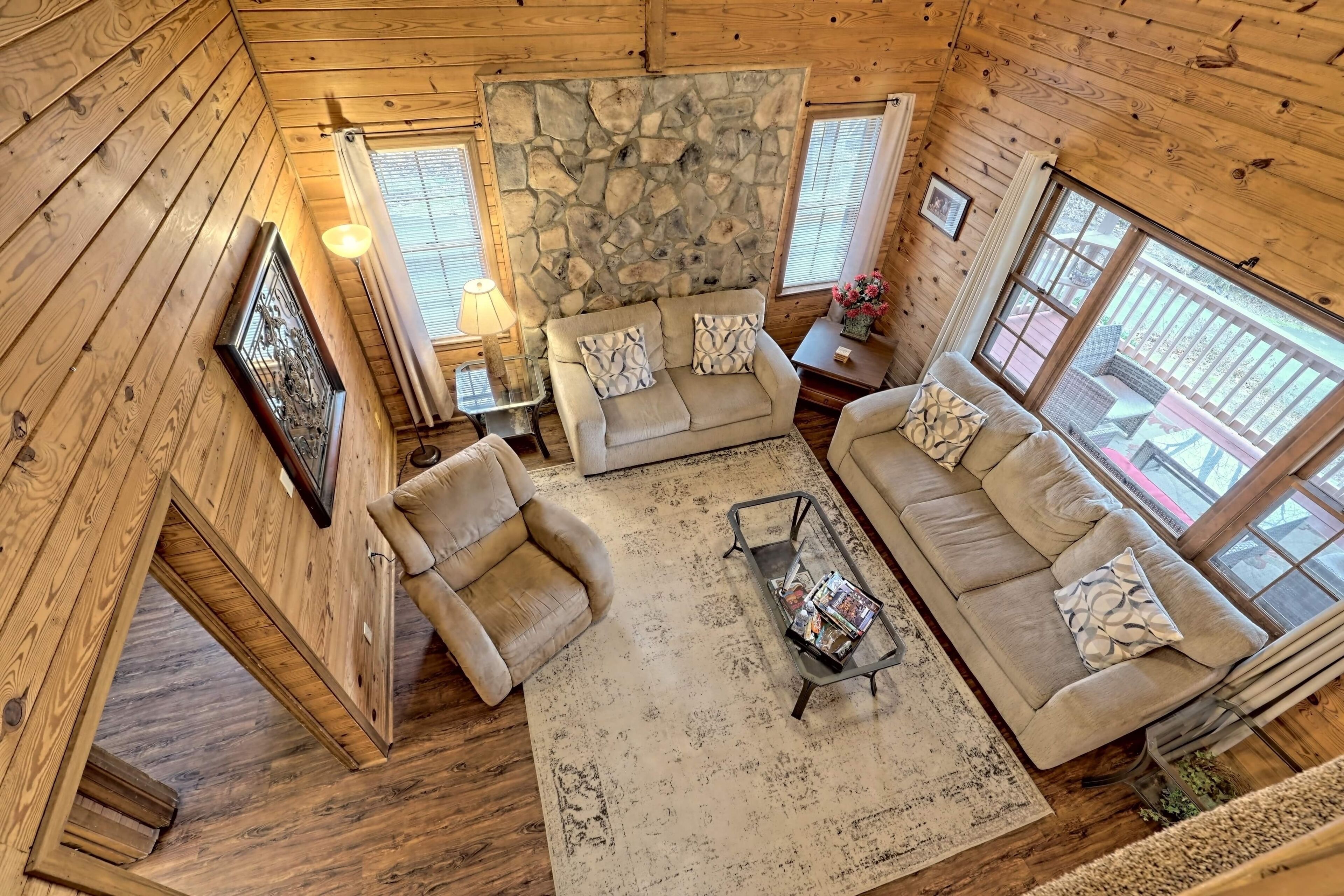 A cozy cabin interior with a stone wall, wooden floors, a sofa set, and a coffee table.