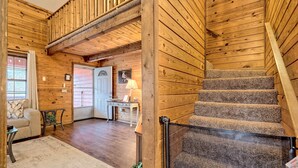 A wooden interior with a staircase, a sofa, a table, and a door.