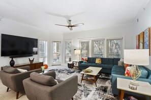 A modern living room with a flat-screen TV, two sofas, a coffee table, and a ceiling fan.