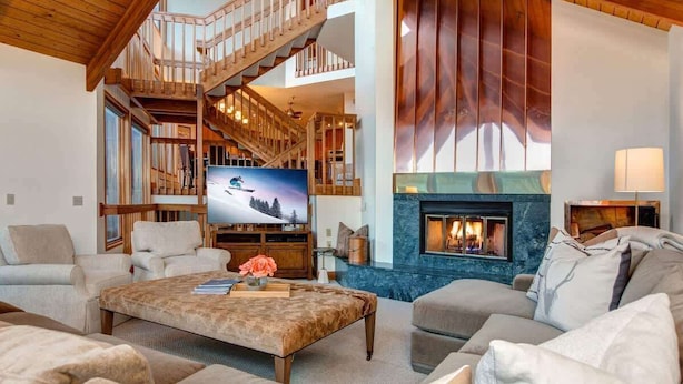 Amplia sala de estar con chimenea, televisión y una escalera que conduce a un nivel superior.