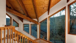 Una escalera de madera con ventanas amplias y vista a árboles.