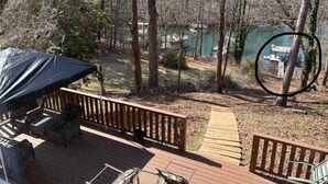 A wooden deck with outdoor furniture, a covered area, and a view of a dock and boats in the background.
