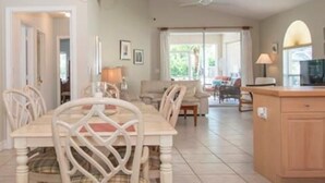 Un'ampia sala da pranzo con un lampadario, un angolo cottura con TV e vista sull'esterno grazie a grandi finestre.