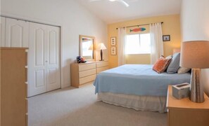 Een slaapkamer met een bed, een kaptafel en een raam met gordijnen.