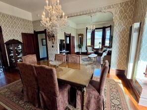 A formal dining room with a large glass table, ornate chairs, and a chandelier. - Gorgeous Historic Victorian Duplex, Quick Walk to Wharf, Beach & Boardwalk (Santa Cruz)