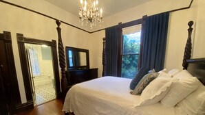 Un dormitorio con una cama grande, un tocador, un espejo y una araña.