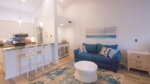 A modern kitchen with white cabinetry, a central island with bar stools, and pendant lighting. - Beach Condo in Sawgrass Country Club - Steps From the Sand! Recently Renovated. (Ponte Vedra Beach)