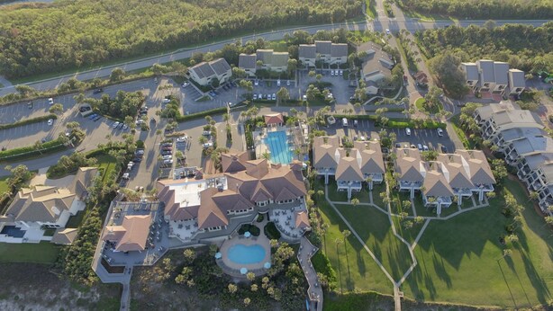 An aerial view of a resort with multiple buildings, a swimming pool, and a beach area. - Beach Condo in Sawgrass Country Club - Steps From the Sand! Recently Renovated. (Ponte Vedra Beach)