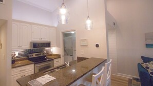 A modern kitchen with white cabinets, a granite countertop, and stainless steel appliances. - Beach Condo in Sawgrass Country Club - Steps From the Sand! Recently Renovated. (Ponte Vedra Beach)