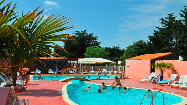 A swimming pool area with multiple pools, lounge chairs, and umbrellas. - Camping La Maurie (Saint-Georges-d'Oleron)