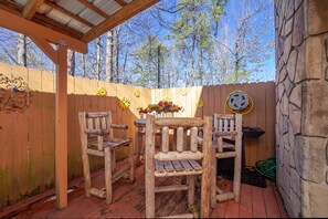 Una terraza de madera con una pérgola, un muro de piedra y una valla de madera con detalles decorativos.