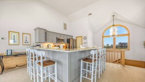Cucina con isola centrale, sgabelli da bar e un'ampia finestra.