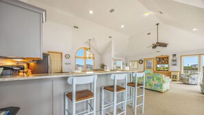Un'ampia cucina con angolo bar, zona pranzo con divano e vista esterna.