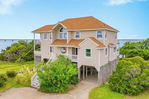 A two-story building with a balcony, a sign indicating a wind direction, and a view of the water.