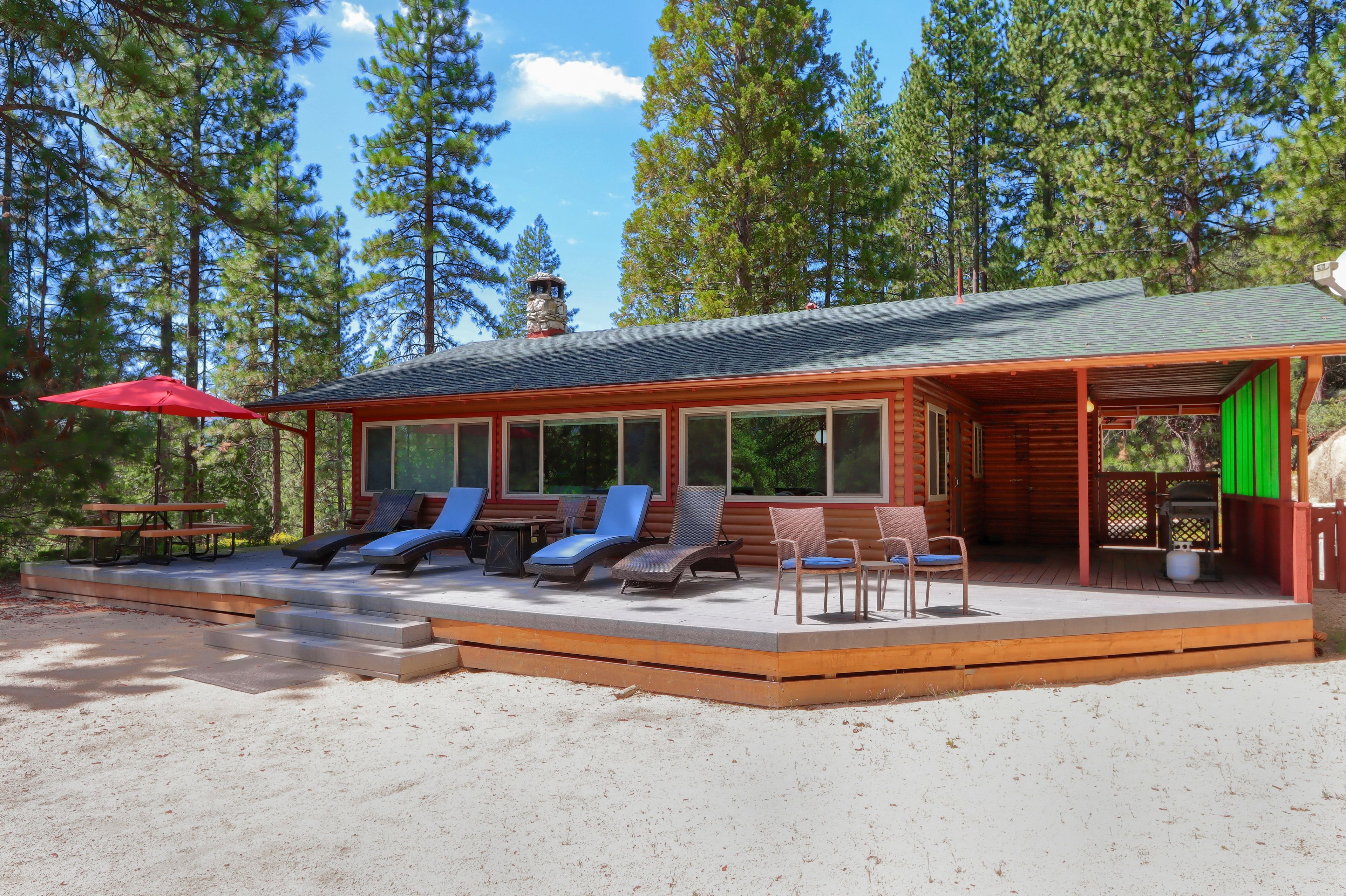 A cabin with a covered patio, outdoor seating, and a stone chimney.