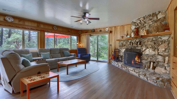 Una sala de estar acogedora con chimenea de piedra, muebles de madera y amplios ventanales.