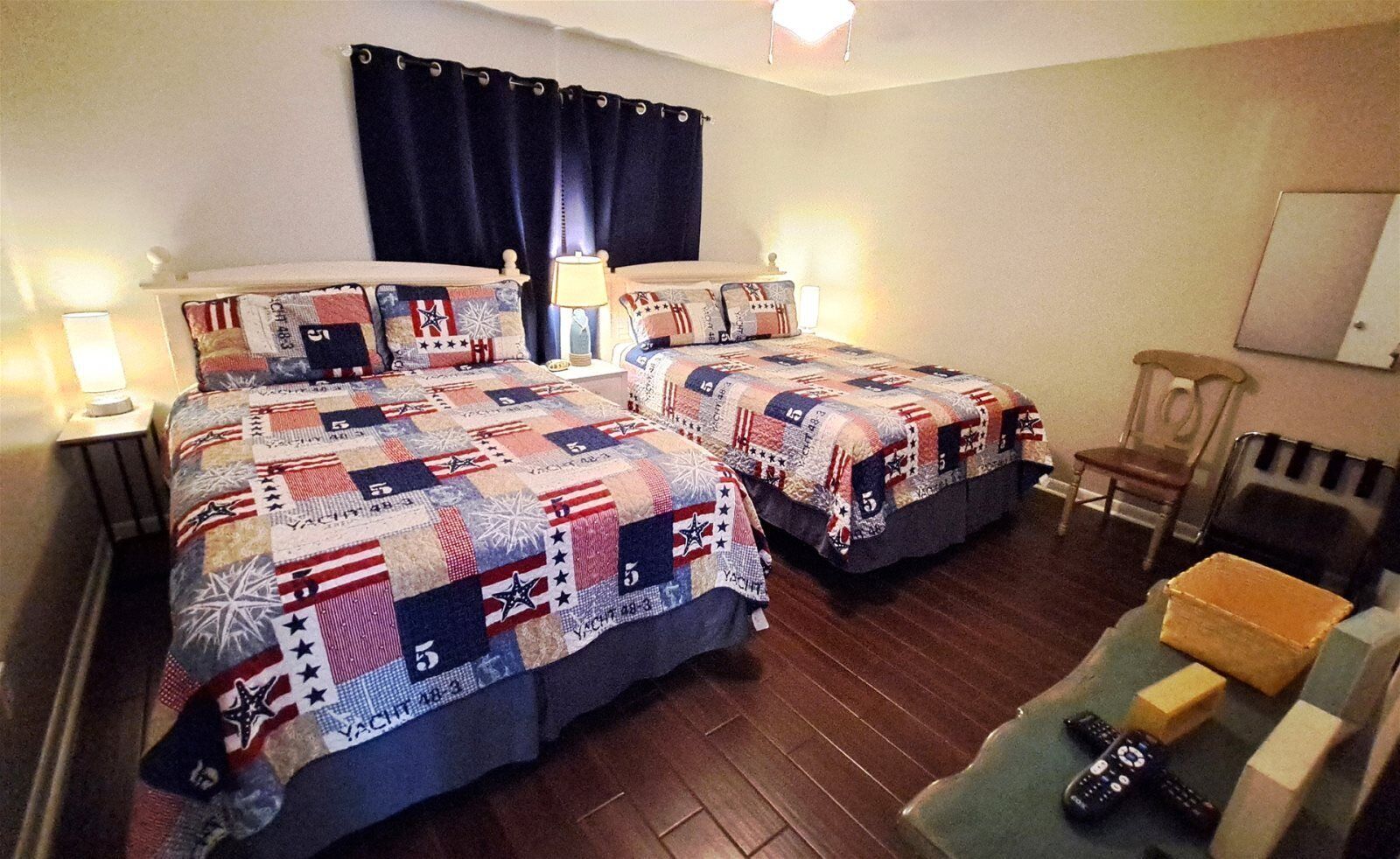 Habitación de hotel con dos camas, una silla, una mesa y una lámpara.