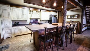 A kitchen with white cabinets, a wooden island, and bar stools. - PEACEFUL PLAYGROUND.  130 acres of fun.  RV hookups available too. (Udall)
