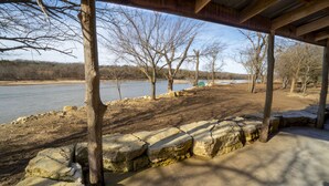 A riverside park with a wooden pavilion, stone steps, and trees. - PEACEFUL PLAYGROUND.  130 acres of fun.  RV hookups available too. (Udall)