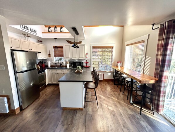 A modern kitchen with a central island, stainless steel appliances, and a farmhouse-style design.