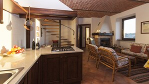 A kitchen with a central island, a dining area with wicker furniture, and a fireplace. - Breathtaking views, excellent food and wine: Barbaresco, Barolo, Alba truffles.. (Trezzo Tinella)