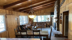 Acogedor interior de cabaña con comedor, asientos y chimenea de piedra.