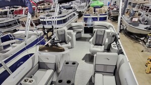 Interior de barco com assentos, uma mesa e um leme.