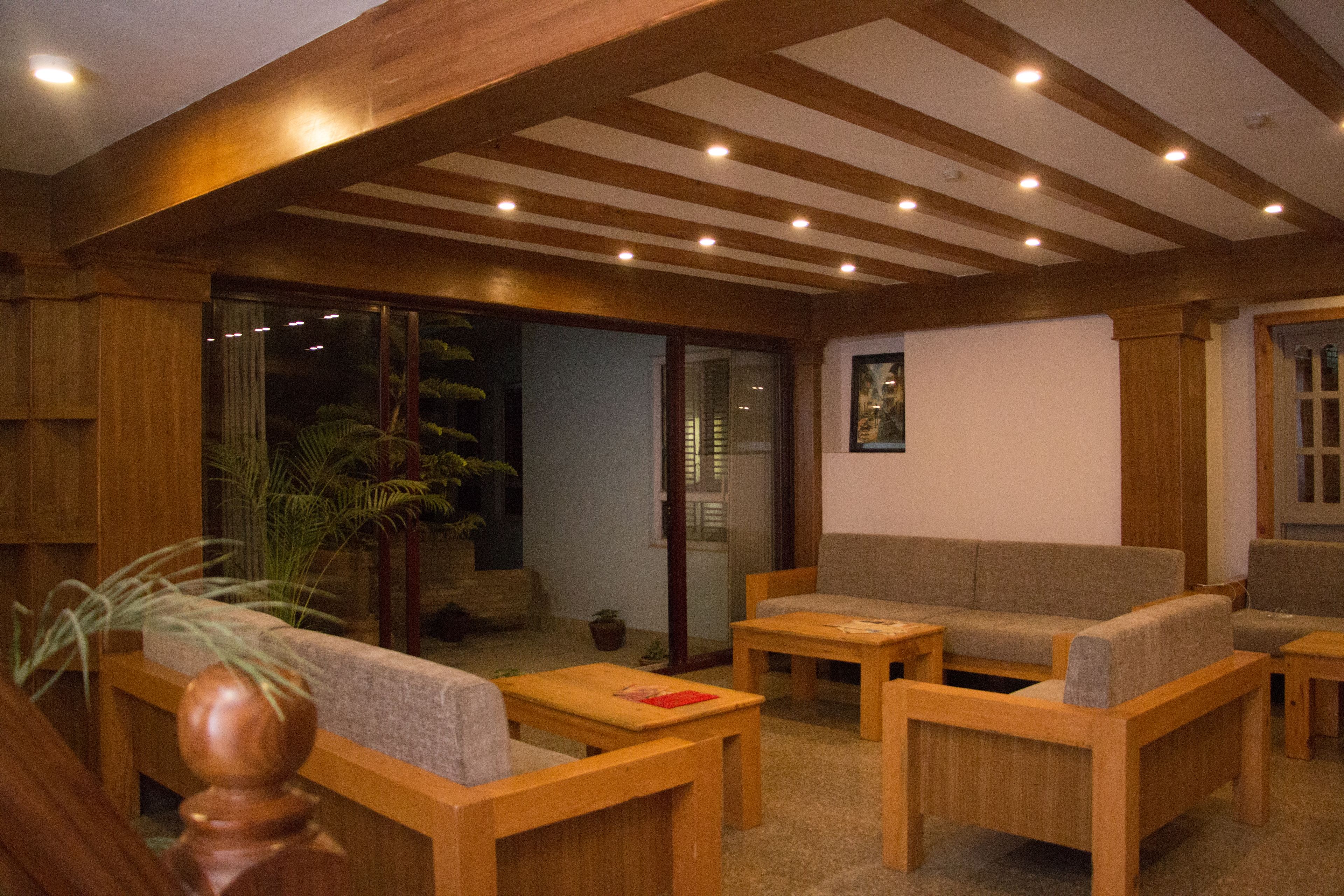 A room with wooden furniture, including a sofa and chairs, a coffee table, and a potted plant.
