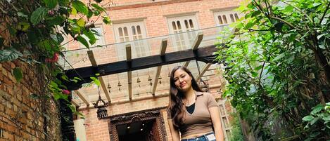 A person standing in a courtyard with a brick building labeled 'CENTRAL BHAKTIAPUR' in the background.