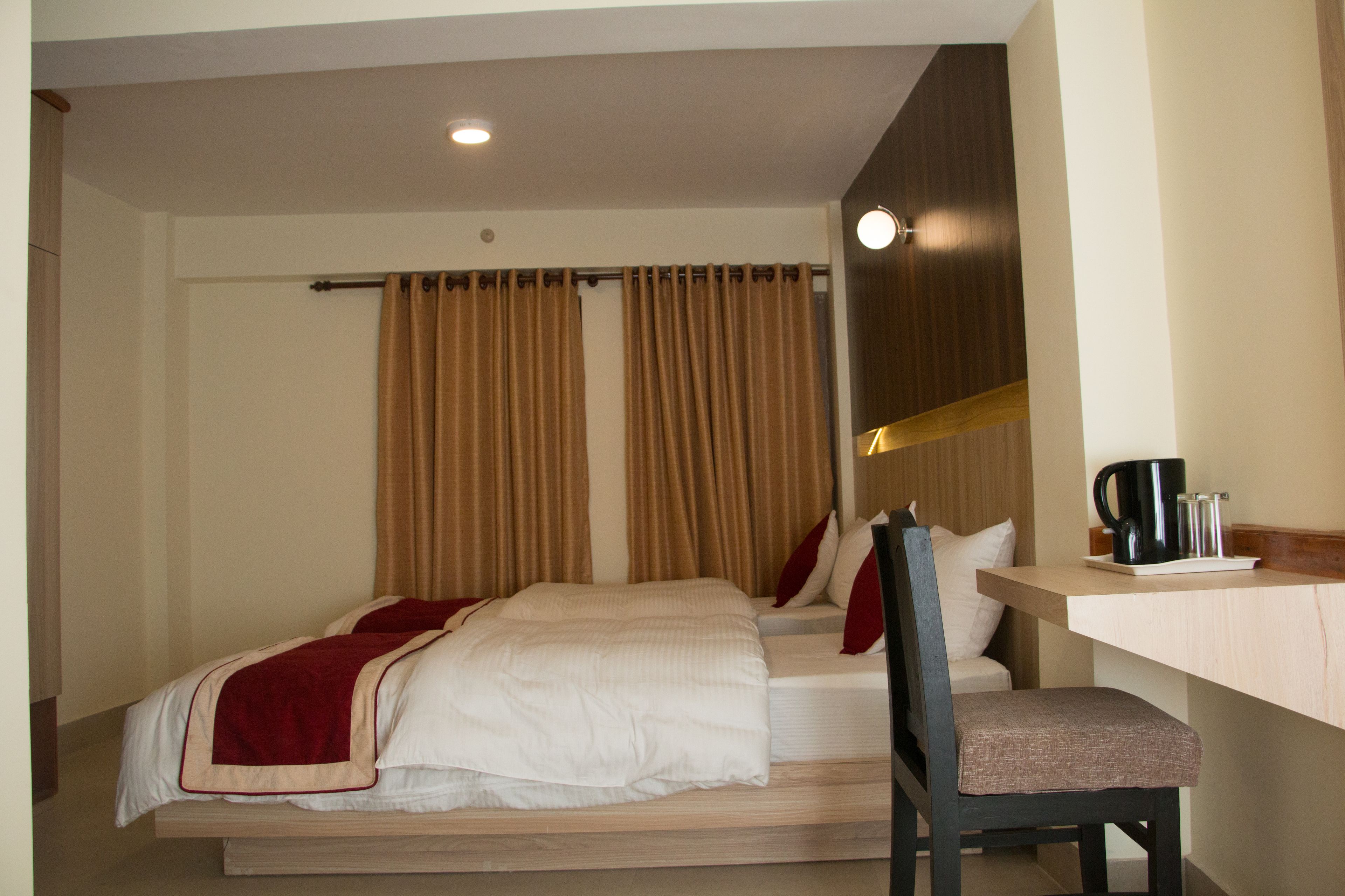 A hotel room with a bed, a chair, a desk, and a coffee maker.