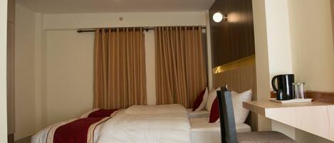 A hotel room with a bed, a chair, a desk, and a coffee maker.