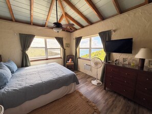 Ein Schlafzimmer mit Bett, Schreibtisch, Stuhl, Fernseher und einem Fenster mit Blick.