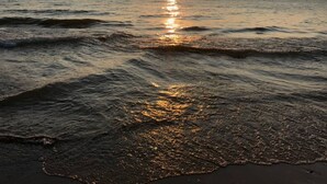 Un coucher de soleil sur l’océan, avec des vagues qui se rapprochent du rivage.