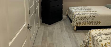 A bedroom with a bed, a dresser, a TV, and a window with blinds.