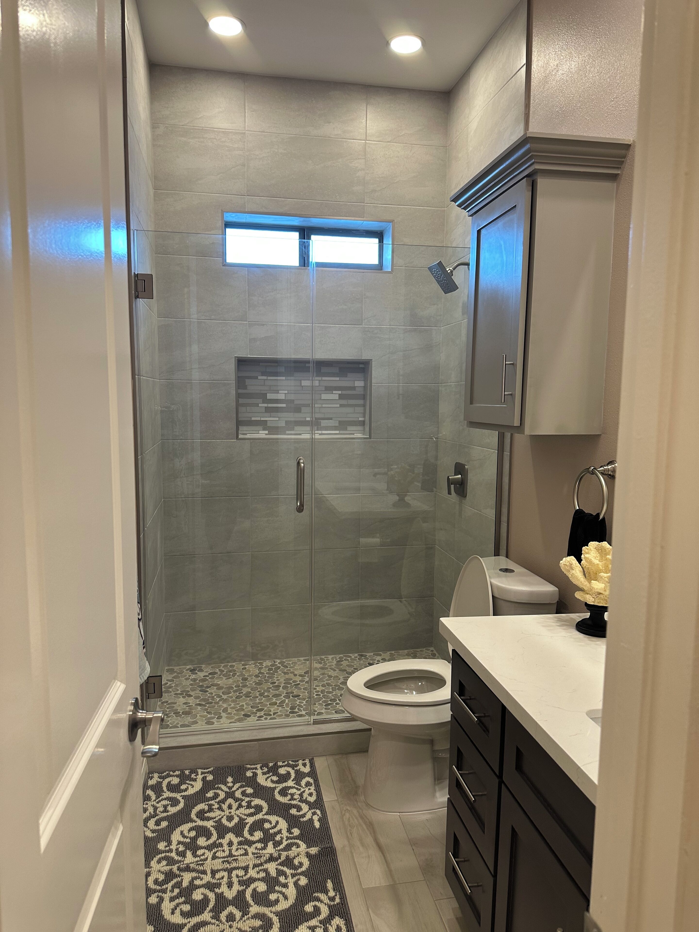A modern bathroom with a glass-enclosed shower, a toilet, and a vanity with a sink.