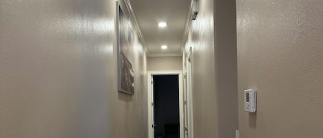 Un pasillo con paredes color beige, piso de madera e iluminación empotrada en el techo.