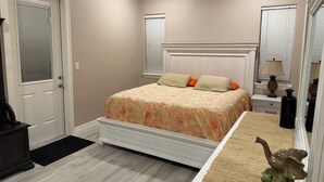 Quarto com cama, mesas de cabeceira, penteadeira, espelho e porta.