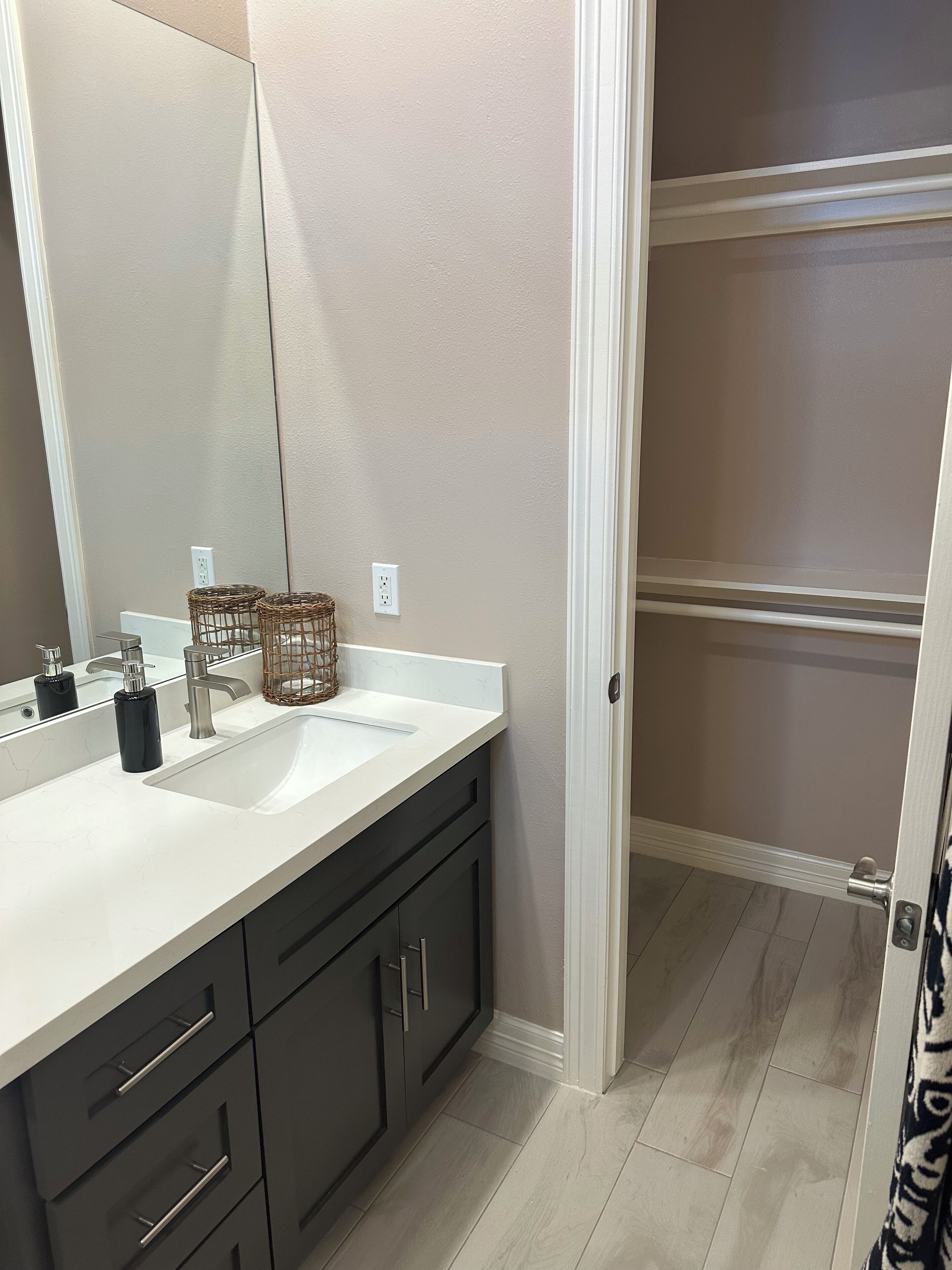 A modern bathroom with a white sink, dark cabinets, and a large mirror.
