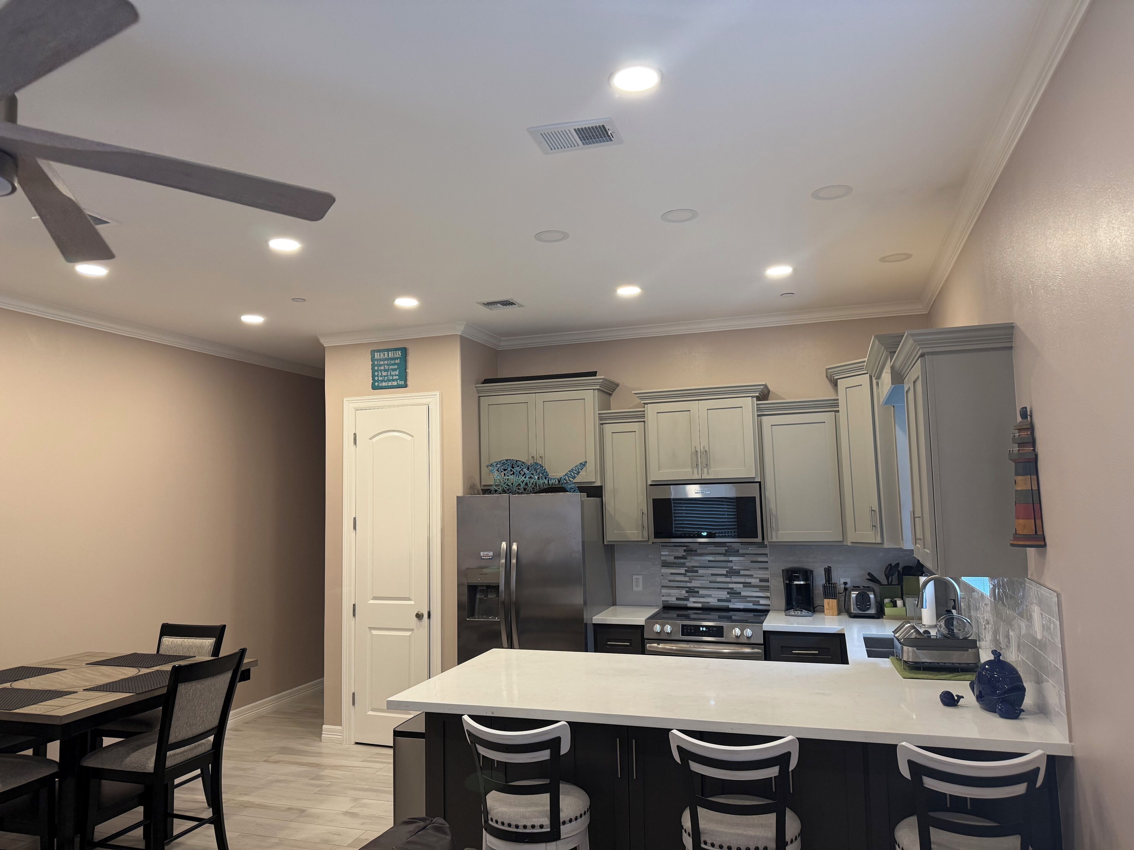 A modern kitchen with a central island, stainless steel appliances, and a ceiling fan.