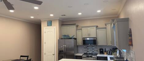 A modern kitchen with a central island, stainless steel appliances, and a ceiling fan.